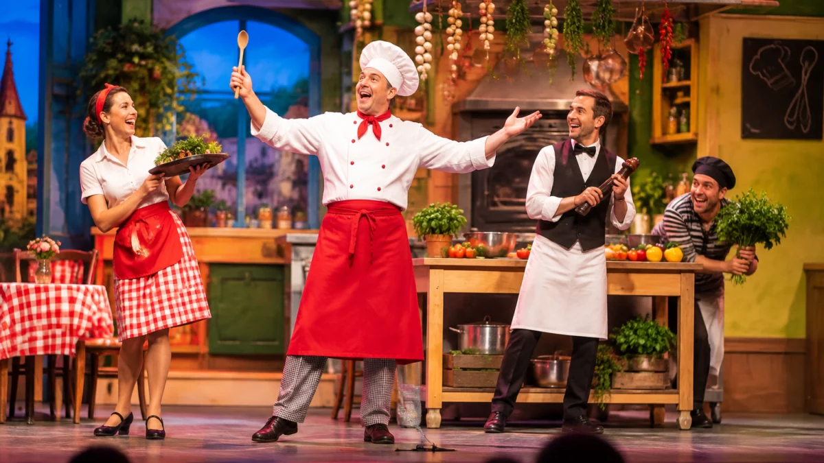Theaterszene mit Schauspielern auf bunter Bühne beim Stück ‚La cuisine de ma cousine‘ – KI-Symbolbild